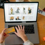 Bancos alertan fraude con agentes de IA para compras Persona realiza una compra en línea con una tarjeta bancaria frente a una computadora portátil