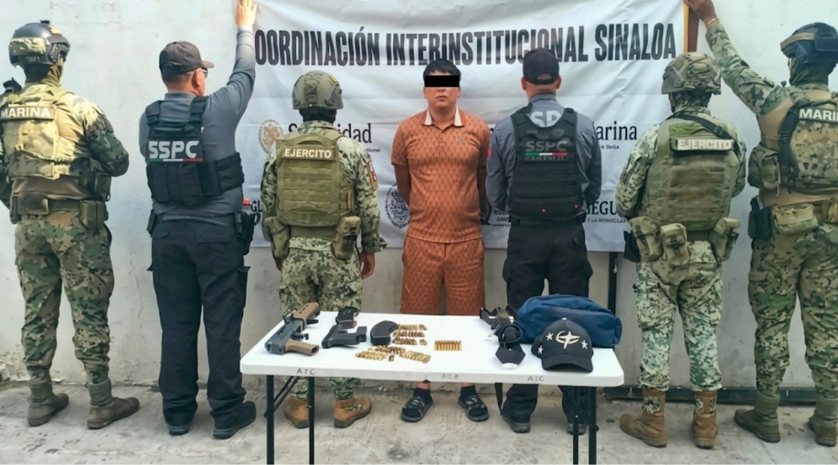 Elemento de seguridad federal custodia a una persona detenida durante un operativo en Sinaloa