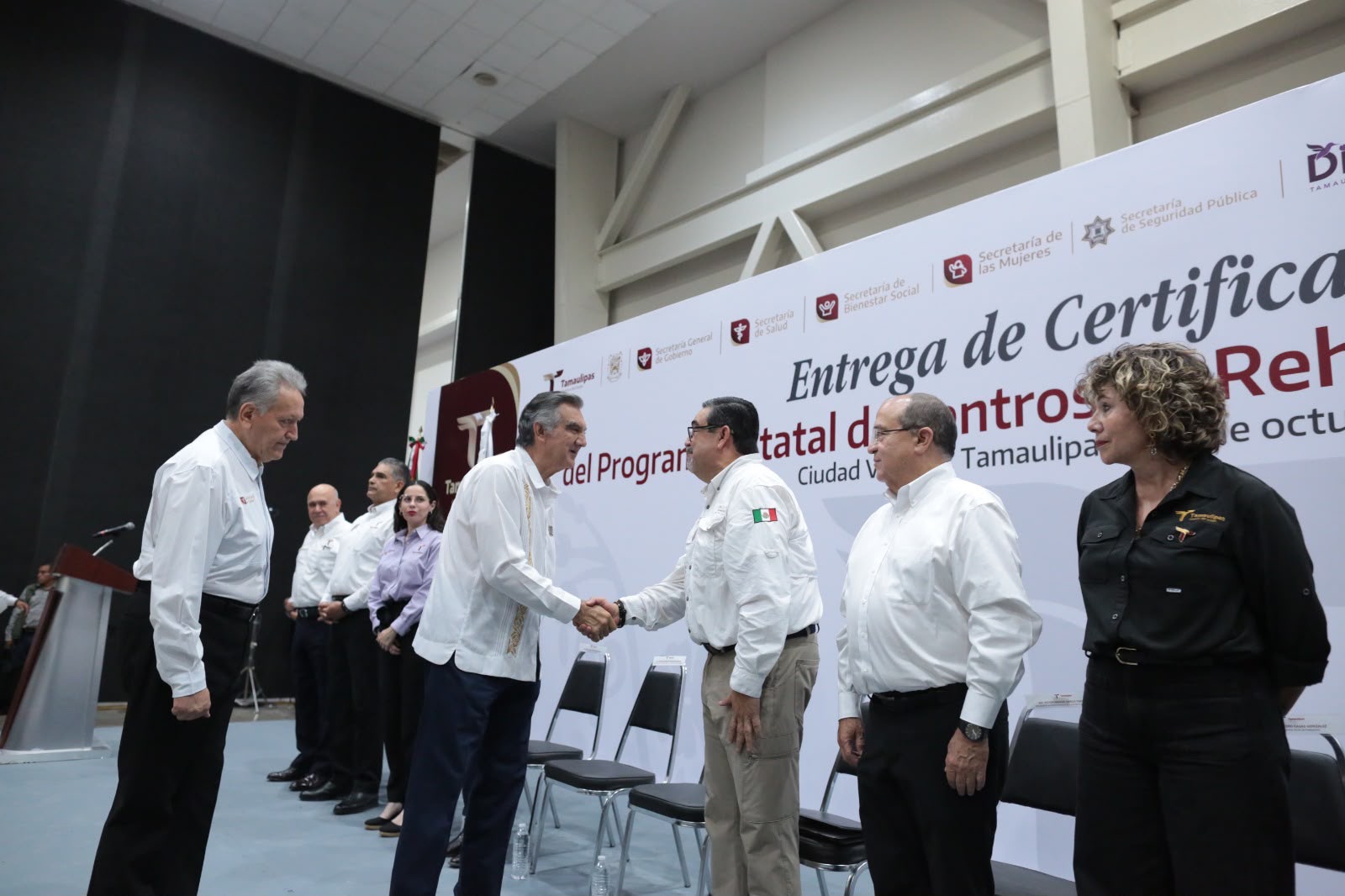 Américo Villarreal saluda a funcionarios durante la entrega de certificados a centros de rehabilitación.