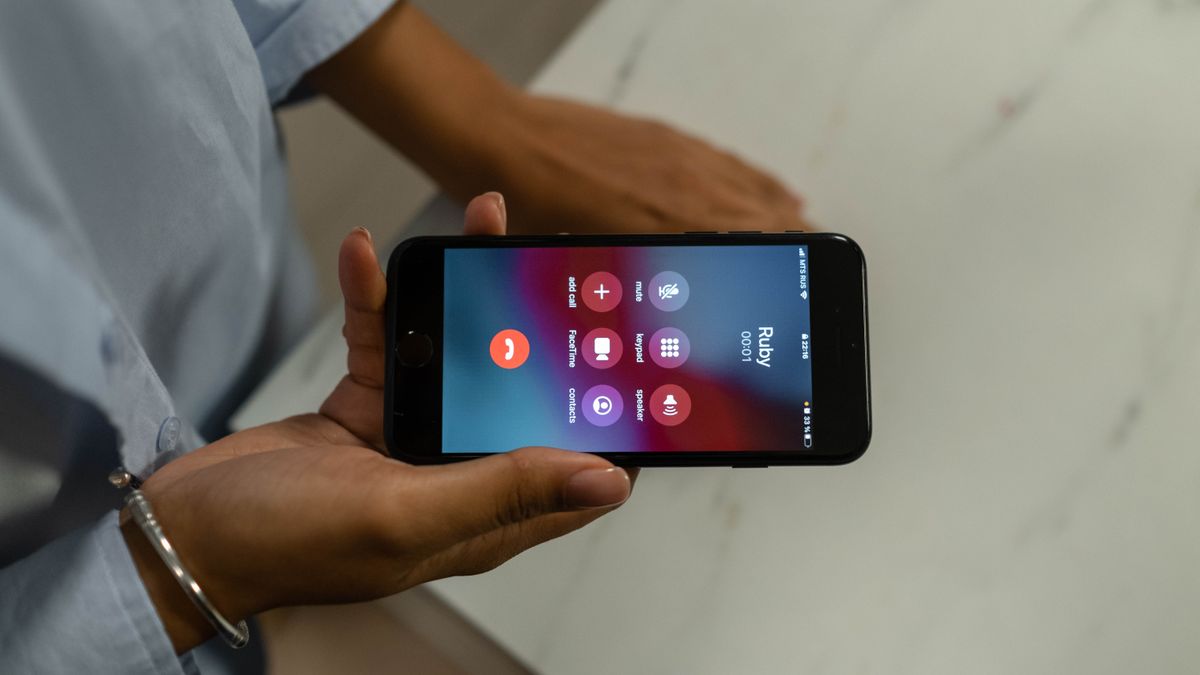 Persona sostiene un teléfono celular con una llamada entrante en pantalla