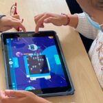 Dos menores utilizan una tableta frente a frente en un entorno educativo