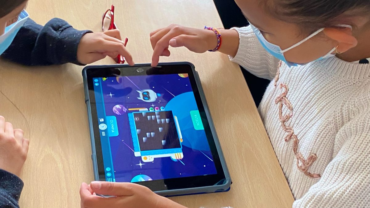 Dos menores utilizan una tableta frente a frente en un entorno educativo