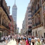 Peatones recorren la avenida Madero con la Torre Latinoamericana al fondo, una escena de actividad económica en Ciudad de México