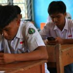 Estudiantes de secundaria usan teléfonos móviles dentro de un salón de clases