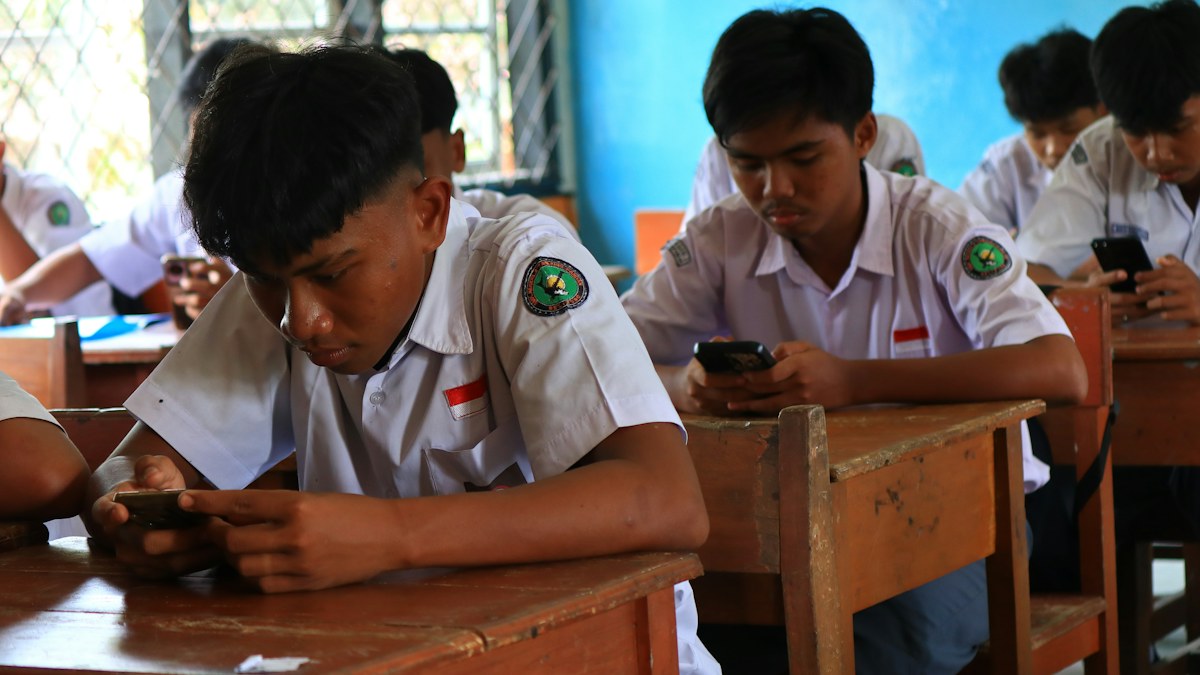 Estudiantes de secundaria usan teléfonos móviles dentro de un salón de clases
