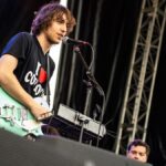 Cameron Winter, vocalista de Geese, toca guitarra y canta en un escenario
