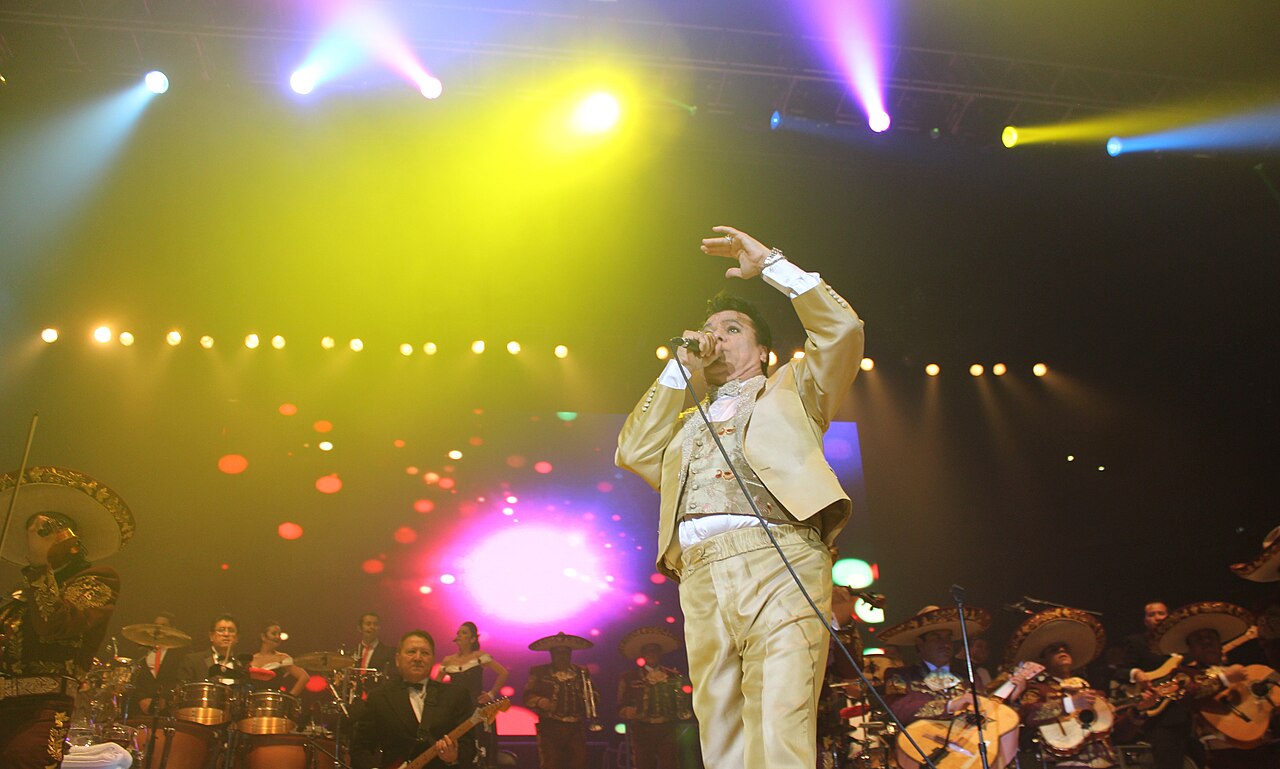 Juan Gabriel canta en un escenario durante un concierto acompañado por músicos