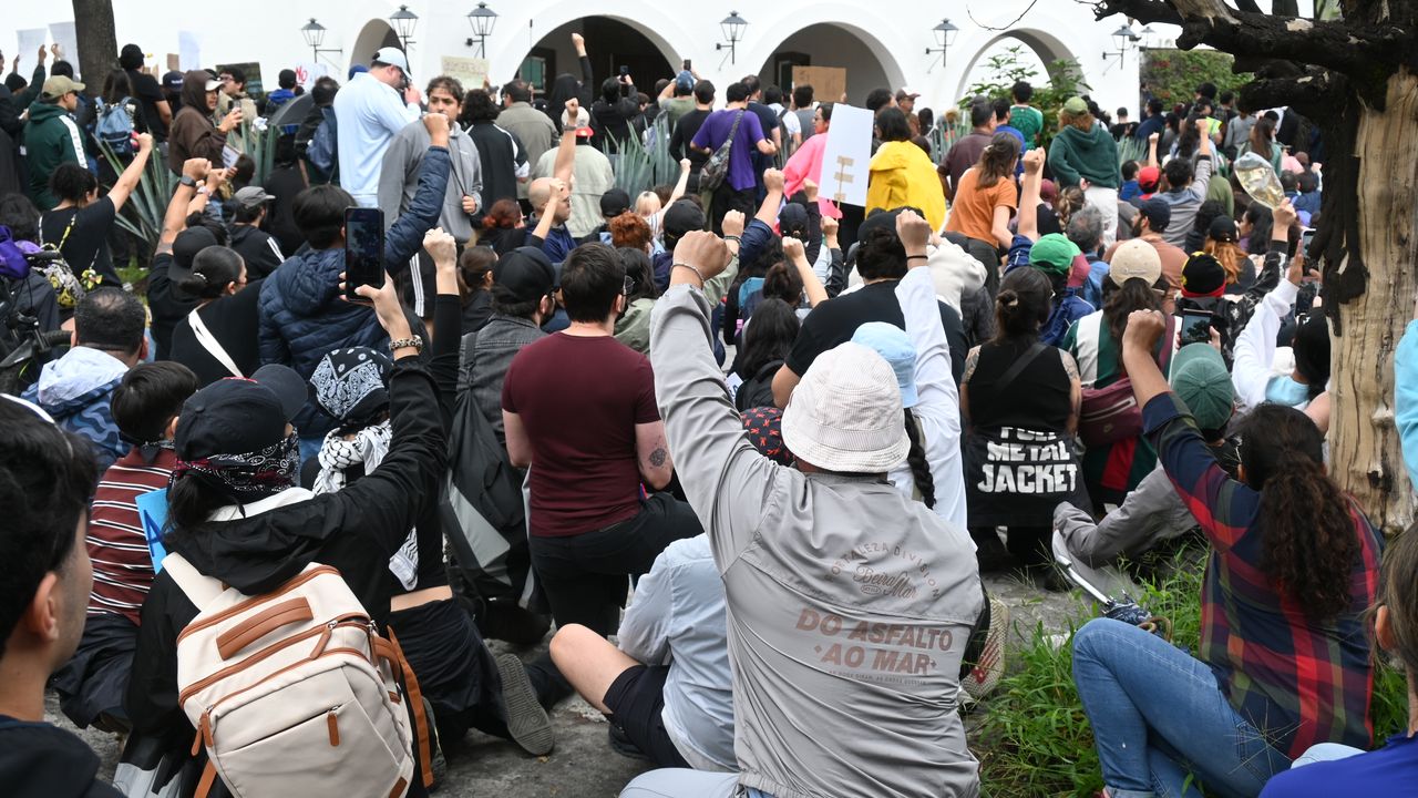 Manifestantes arrodillados frente a policías durante la protesta por agua limpia en Guadalajara