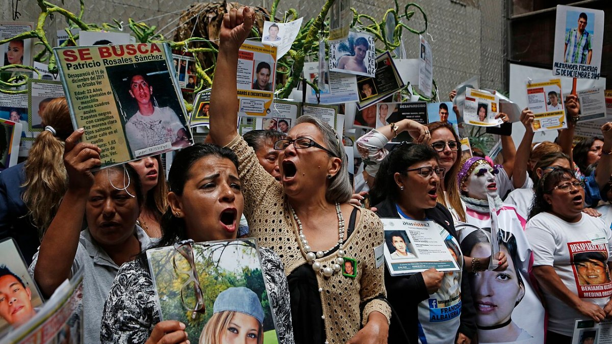 Familiares de personas desaparecidas sostienen fotografías durante un acto público en México