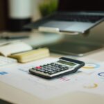 INE rechaza calendario para nuevo sistema contable Calculadora sobre informes financieros junto a una computadora portátil