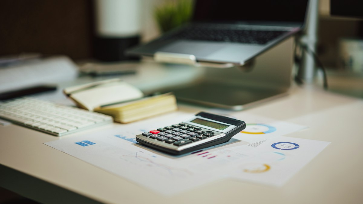 Calculadora sobre informes financieros junto a una computadora portátil
