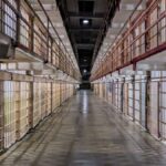 Pasillo vacío de una prisión con celdas y barrotes a ambos lados