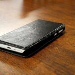 CADDE: reglas antiextorsión arrancan sin recursos extra Teléfono móvil con funda negra sobre una mesa de madera; fotografía ilustrativa de archivo, no vinculada con una denuncia.